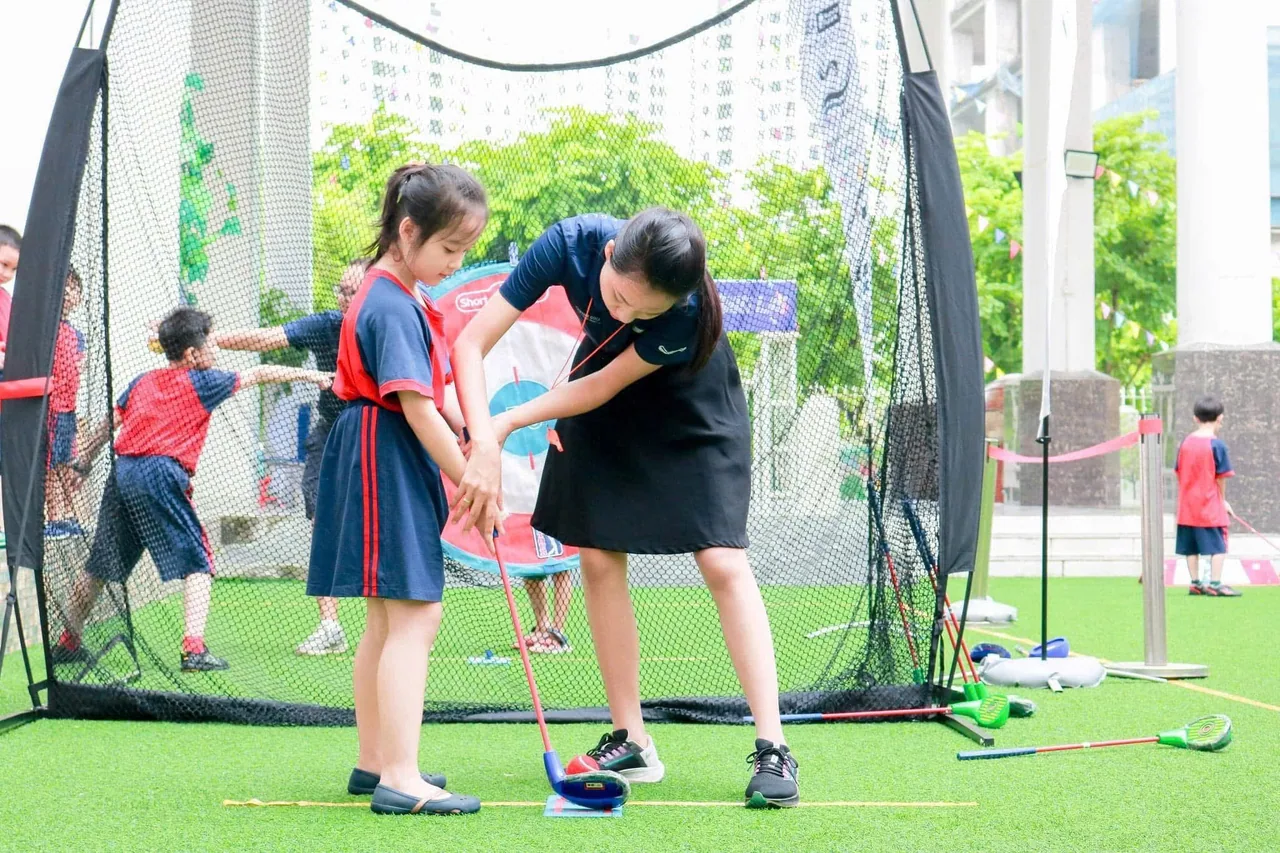 Huấn luyện viên hướng dẫn trẻ tập golf với dụng cụ SNAG